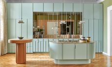 Blue panelled kitchen with rounded island and mirrored splashback