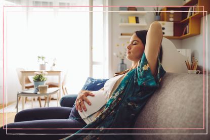 A pregnant woman on the sofa with her eyes closed whilst experiencing pregnancy headaches