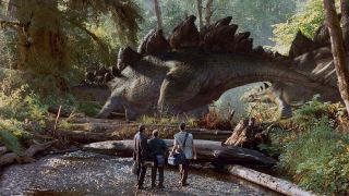 Screenshot from The Lost World: Jurassic Park (1997). A Stegosaurus walks past the protagonists.