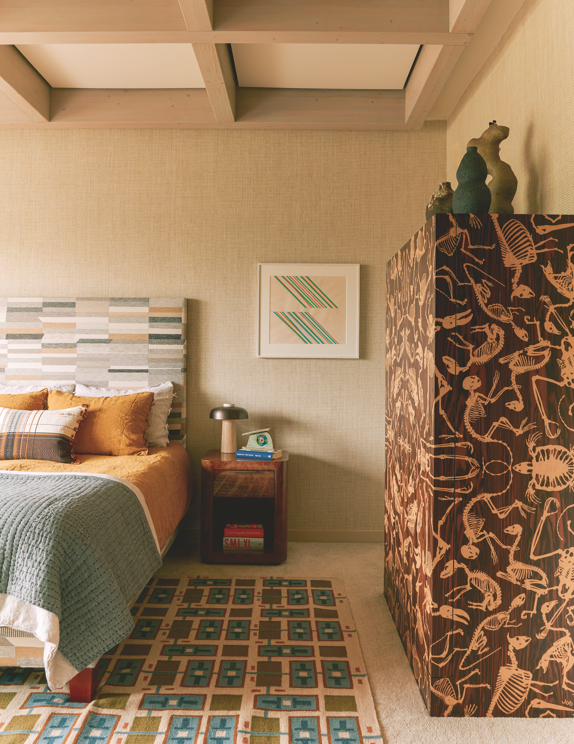 A modern bedroom with a large printed cabinet on the right wall, a patterned rug underneath the bed and a nightstand to the right.