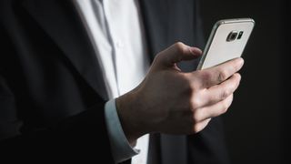 Man holding smartphone - using a notetaking app.