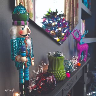 A mantelpiece with a sequined Nucracker and other Christmas decorations