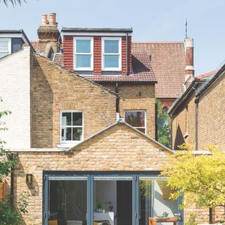 Home rear exterior with patio doors at ground level and a dormer window in the roof