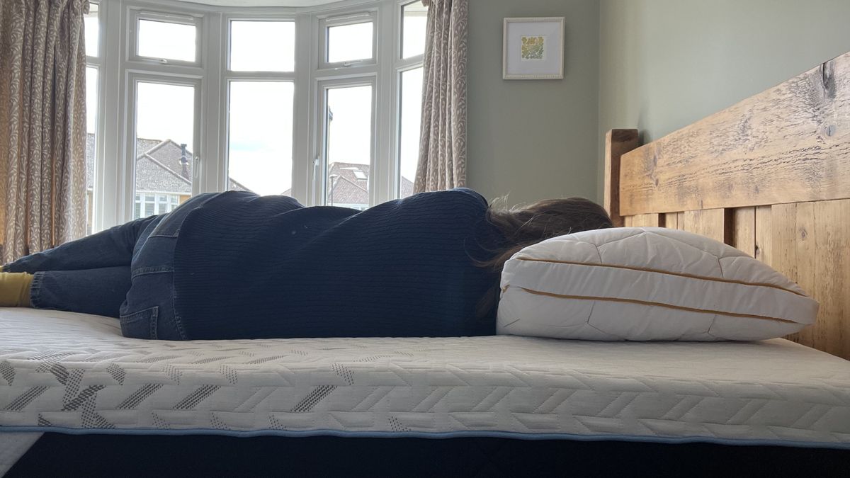 reviewer laying on her side to demonstrate side sleeping position on the nectar classic hybrid mattress