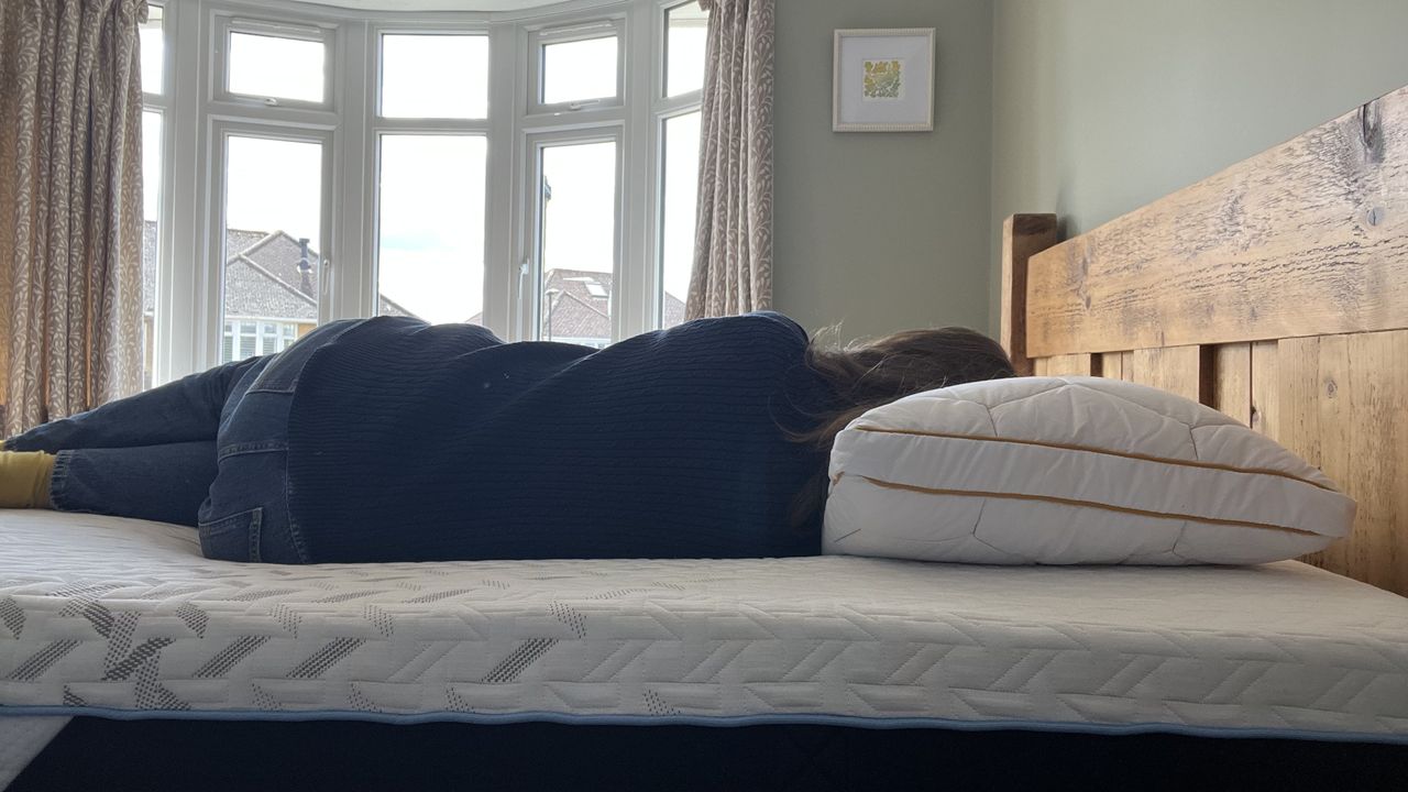 reviewer laying on her side to demonstrate side sleeping position on the nectar classic hybrid mattress