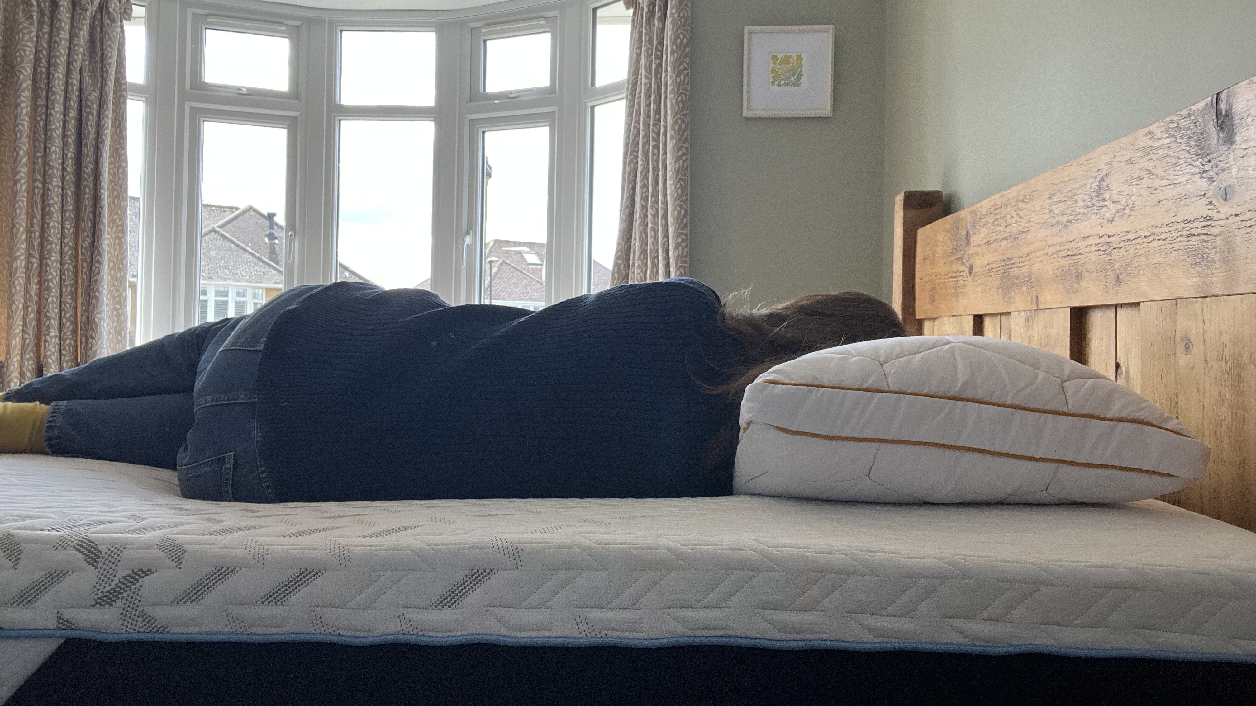 reviewer laying on her side to demonstrate side sleeping position on the nectar classic hybrid mattress