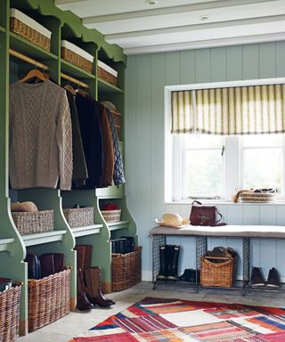 A mudroom with a green open shelving unit divided into personal sections, and woven baskets for boots