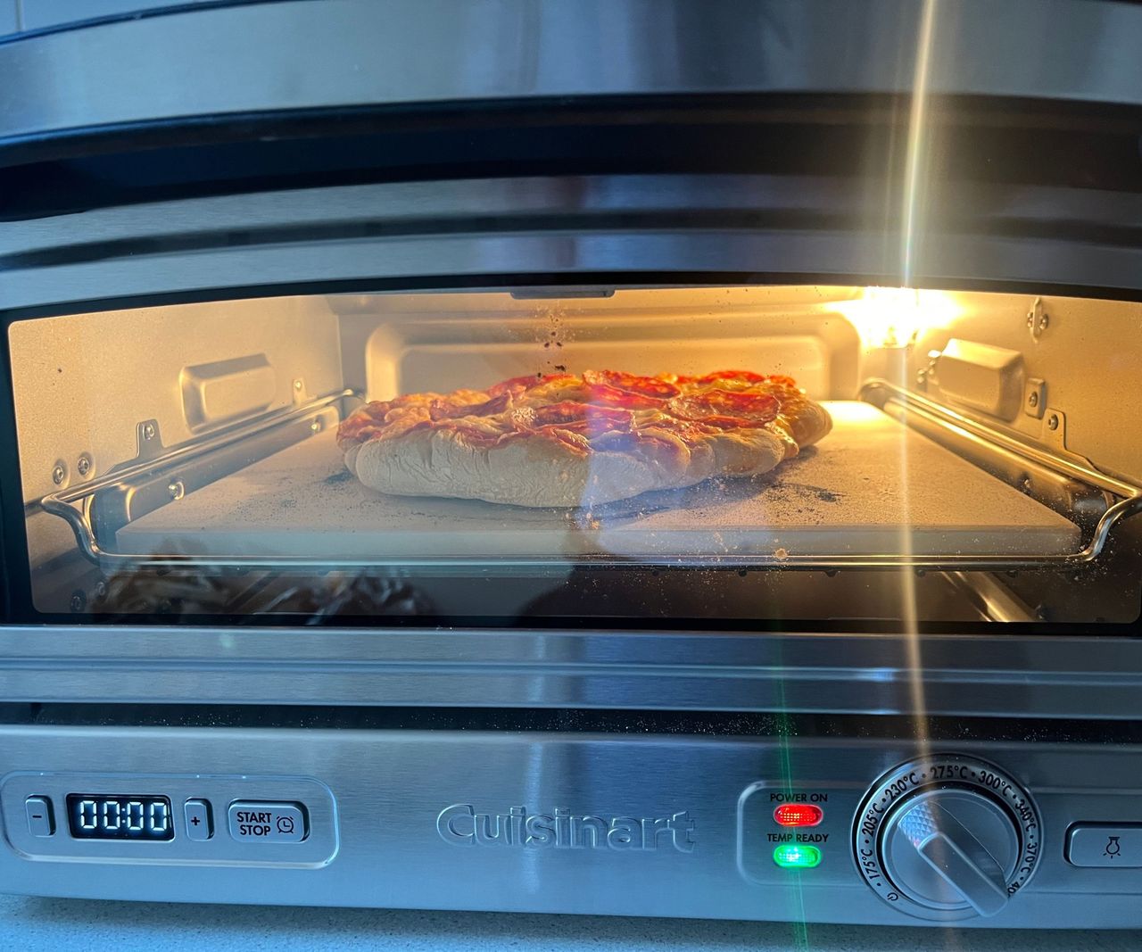 A pepperoni pizza cooking in the Cuisinart Indoor Pizza Oven