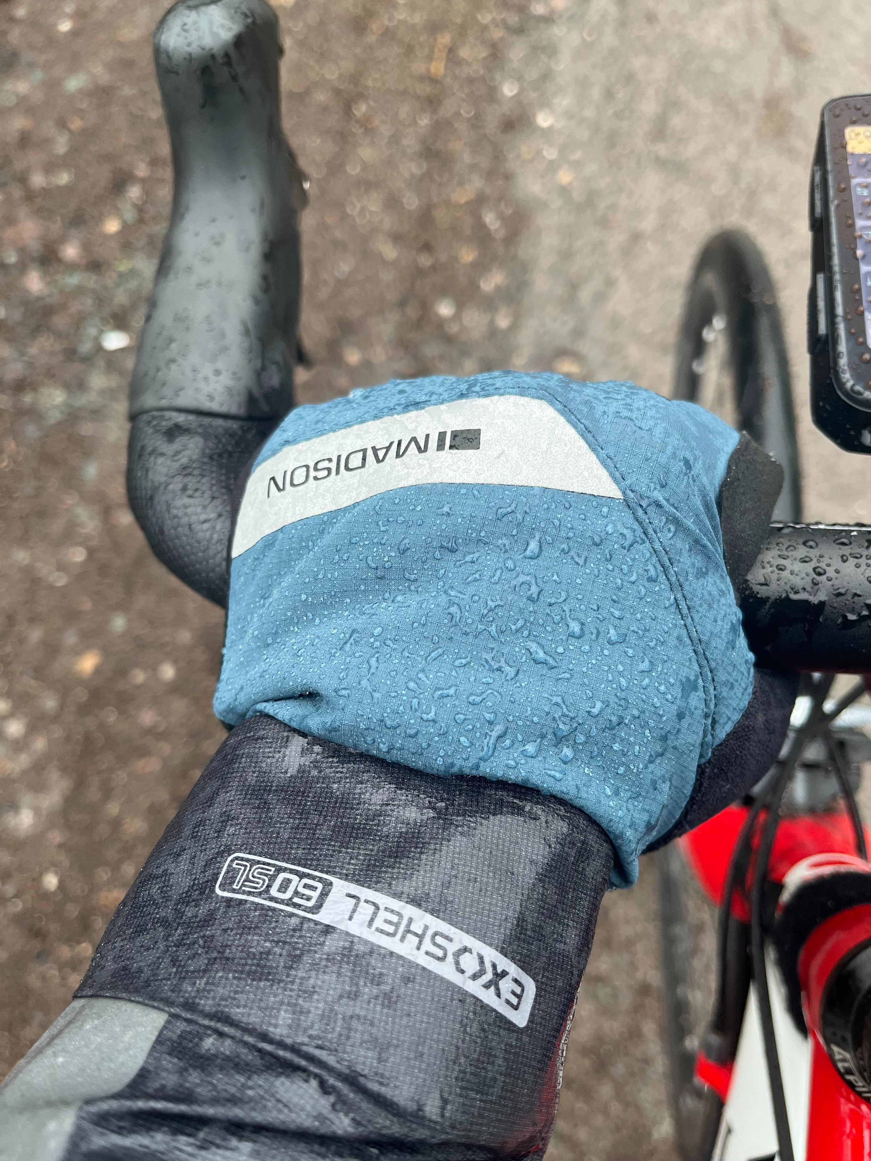 Un ciclista con guantes de invierno Madison DTE sujetando el manillar bajo la lluvia