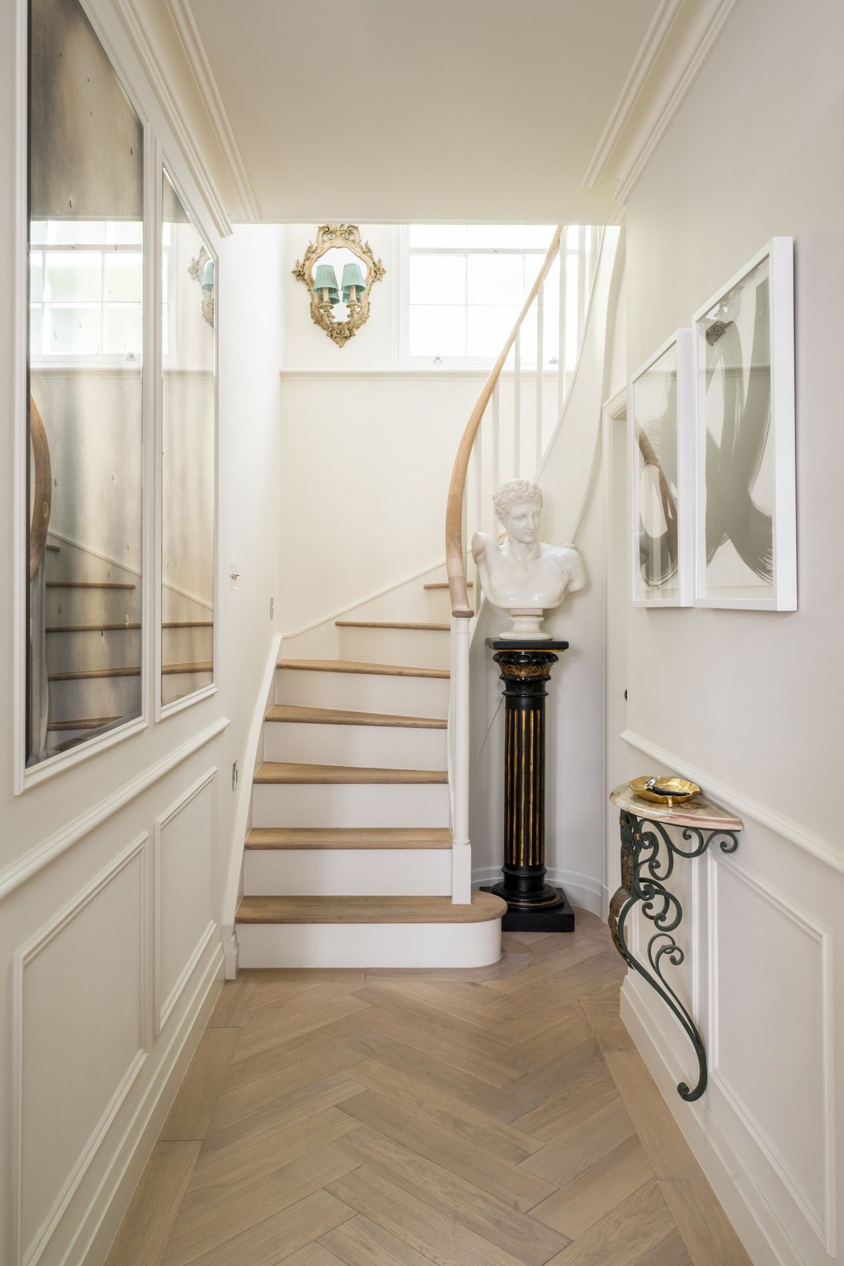 A white panelled hallway with light parquet wooden flooring and a staircase