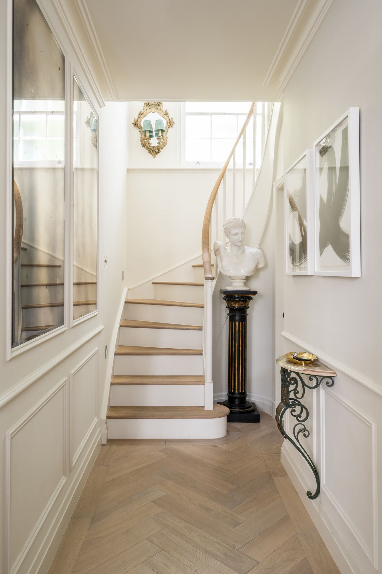 A white panelled hallway with light parquet wooden flooring and a staircase