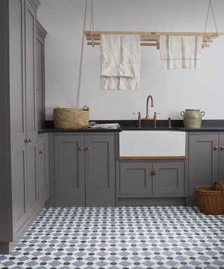 A grey utility room with blue and white patterned vinyl flooring.