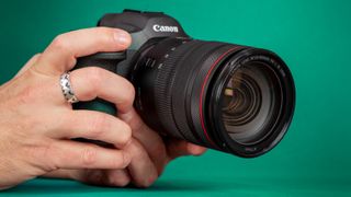 Canon EOS R5 Mark II in person's hands against a green backdrop