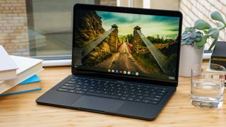 Google Pixelbook Go on a wooden desk with a glass of water.