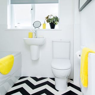 bathroom with vinyl flooring in latte white and jet black and yellow bath mat and towel