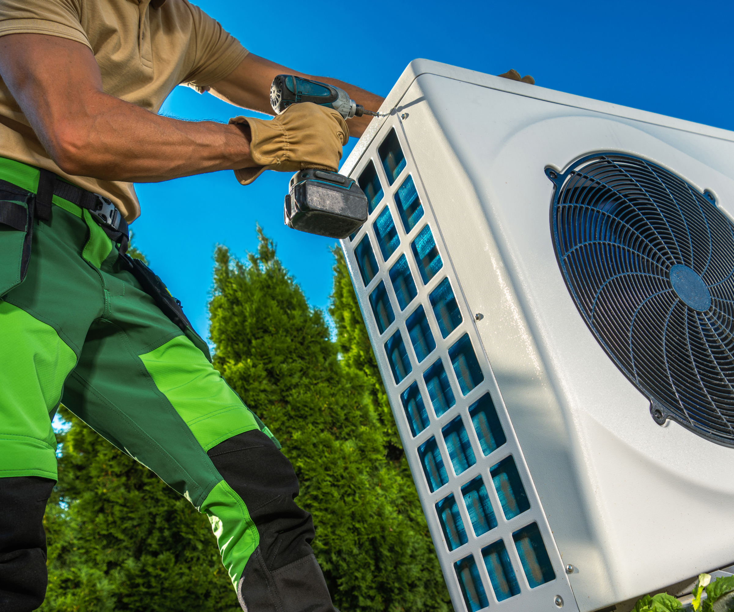heat pump installer screwing heat pump casing outside in garden