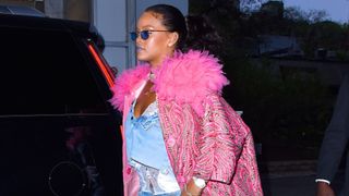 Rihanna wearing a cropped denim shirt, ripped jeans, lace white camisole top, pink coat and sunglasses