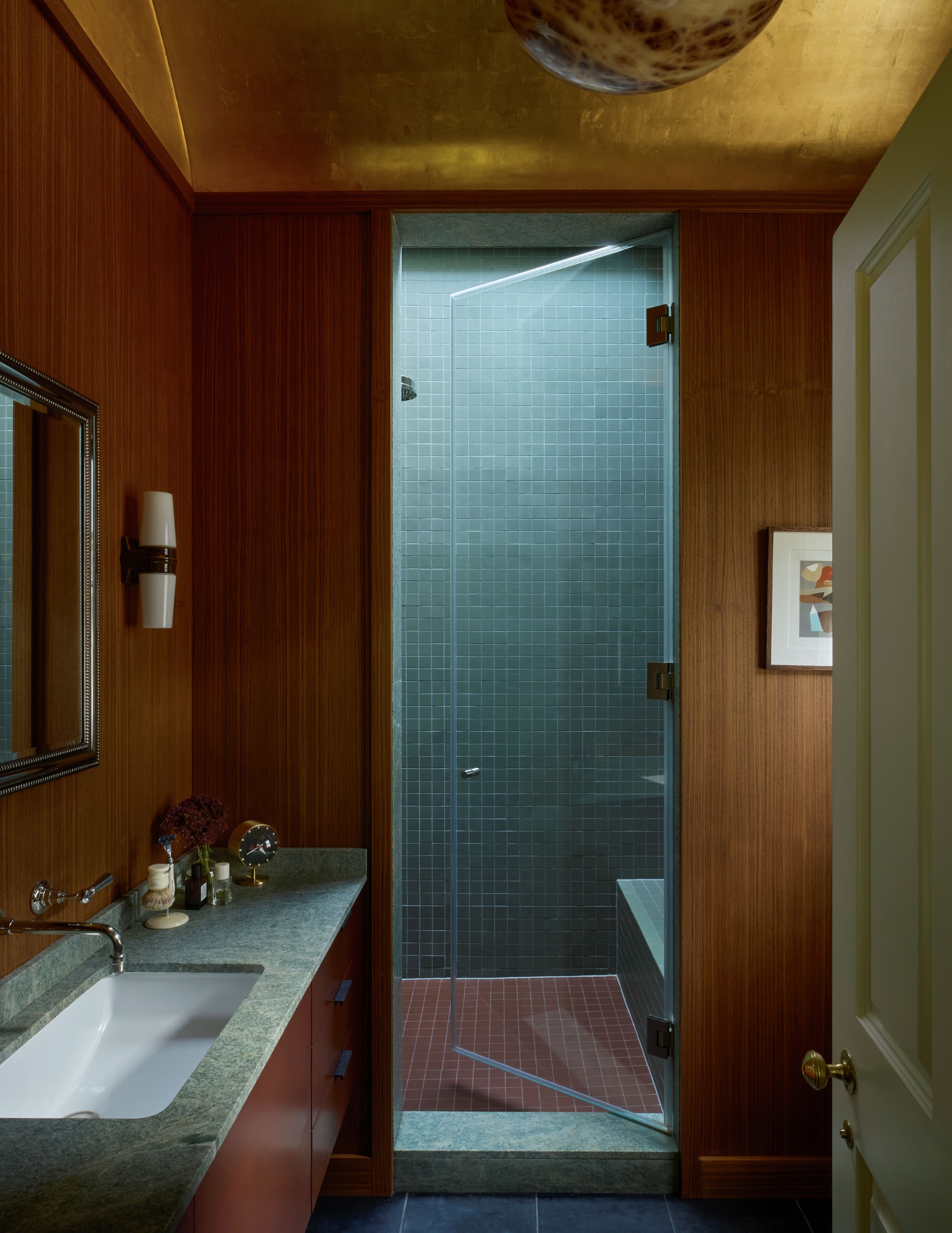 small bathroom with wooden walls, a gold ceiling, green granite counters, and a blue and red tiled shower room