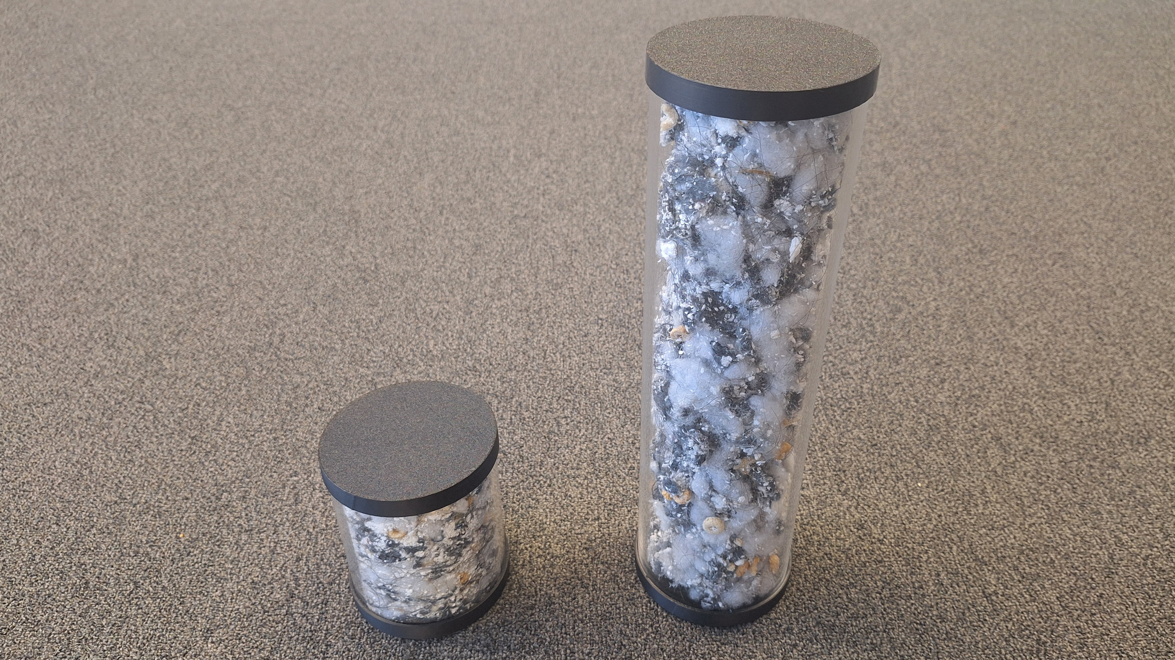 Tiny canister of compressed dirt, next to a larger one showing the same amount of dirt, but without any compression