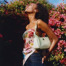 Model wearing a colourful scarf as a bandeau top with a white Kate Spade handbag