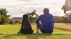 A man and his dog take in a country view. 