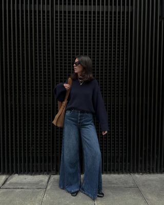 Fran wears a COS navy jumper, blue jeans, brown bag