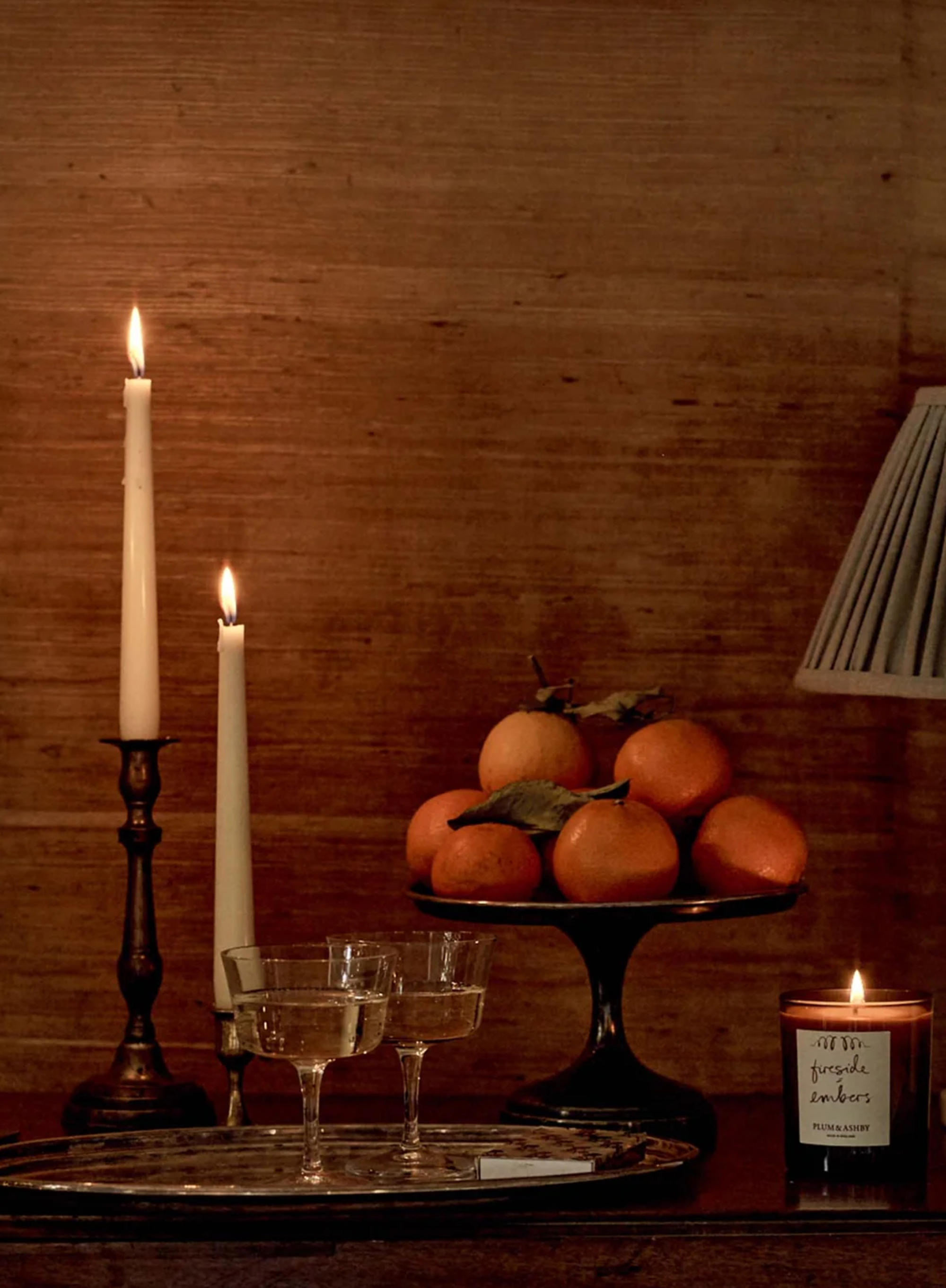 side table with glassware, candlesticks, bar tray, and pedestal styled with oranges