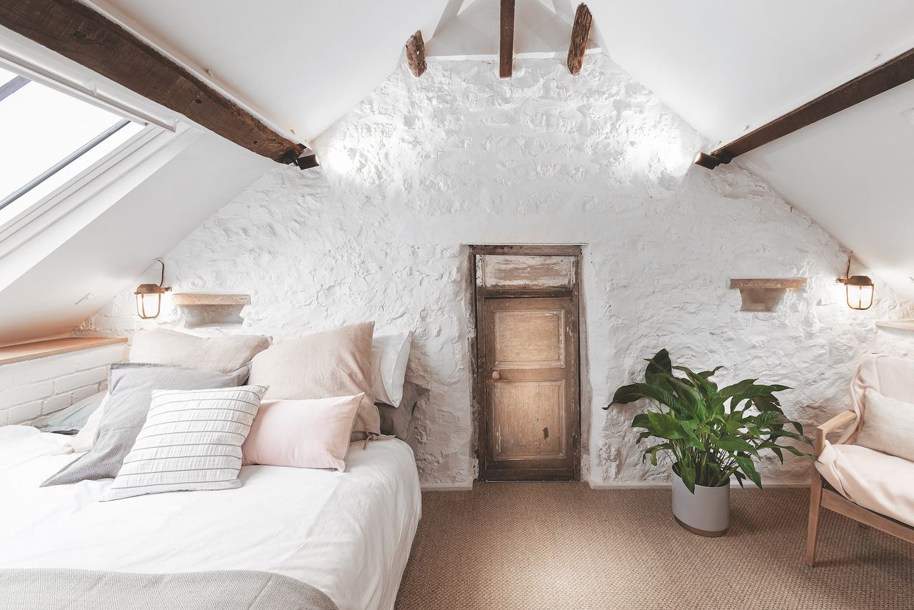 bedroom with white painted stone walls and vaulted ceiling