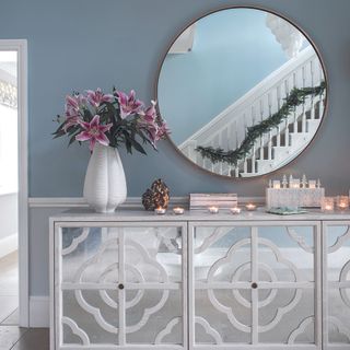 hallway with grey wall, round mirror and mirrored cabinet