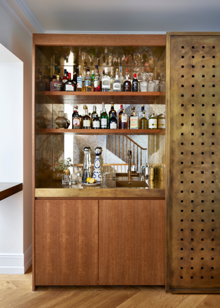 A hosting closet with a mirror and shelves of bottles