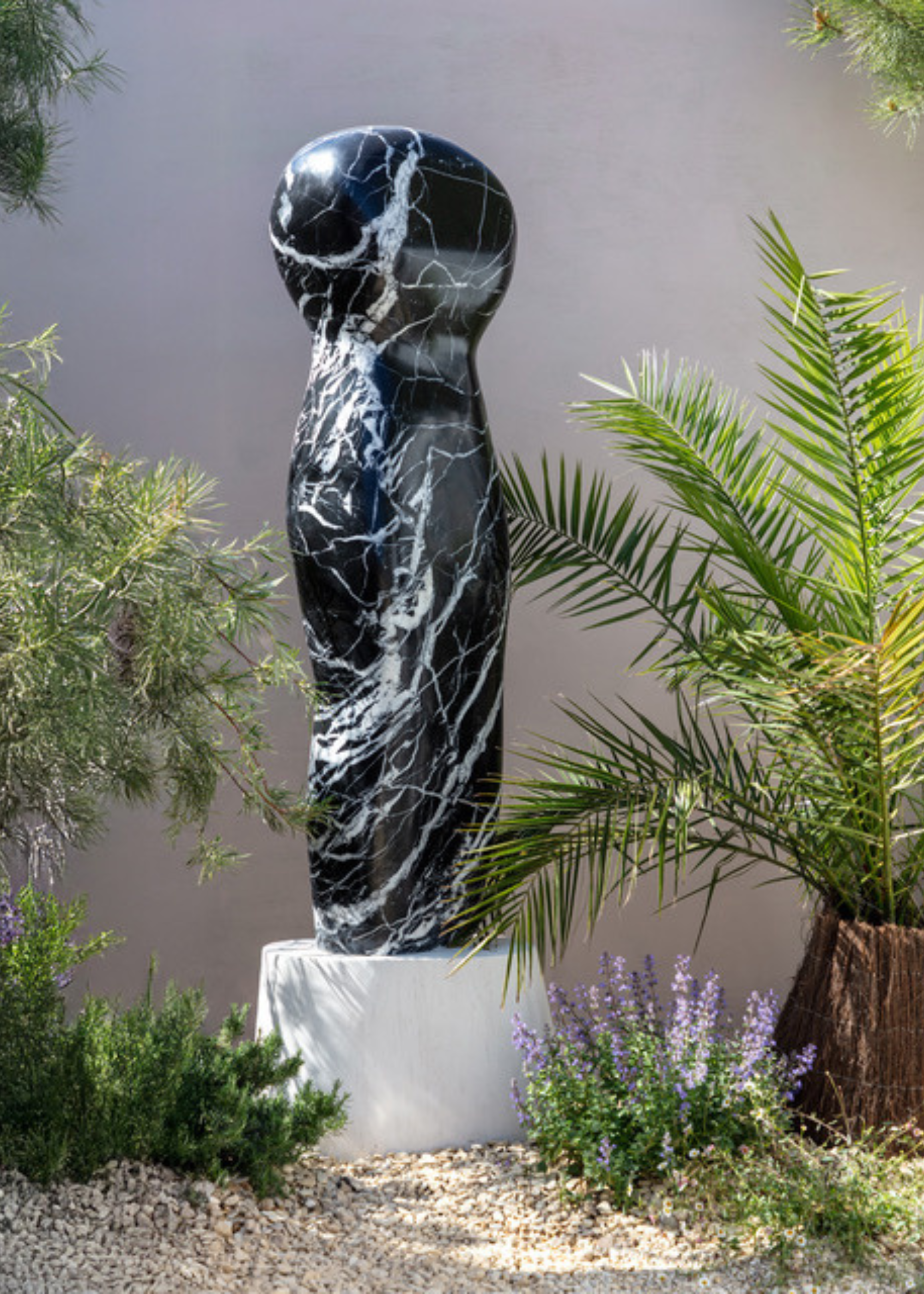 black marble sculpture in a garden surrounded by plants