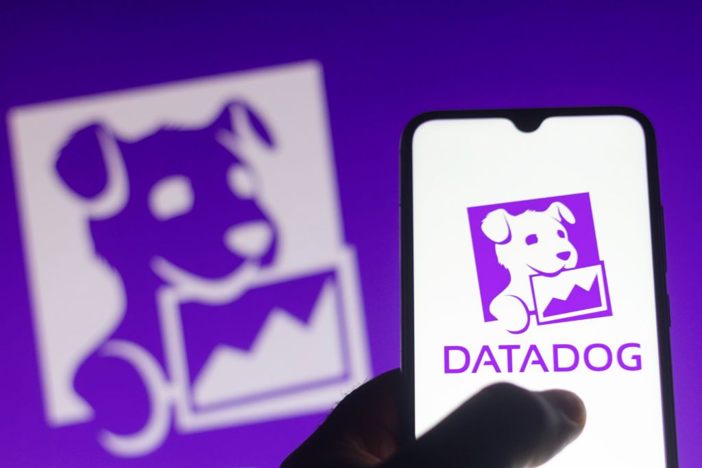 Purple Datadog logo of puppy holding a chart in its mouth on smartphone and in background