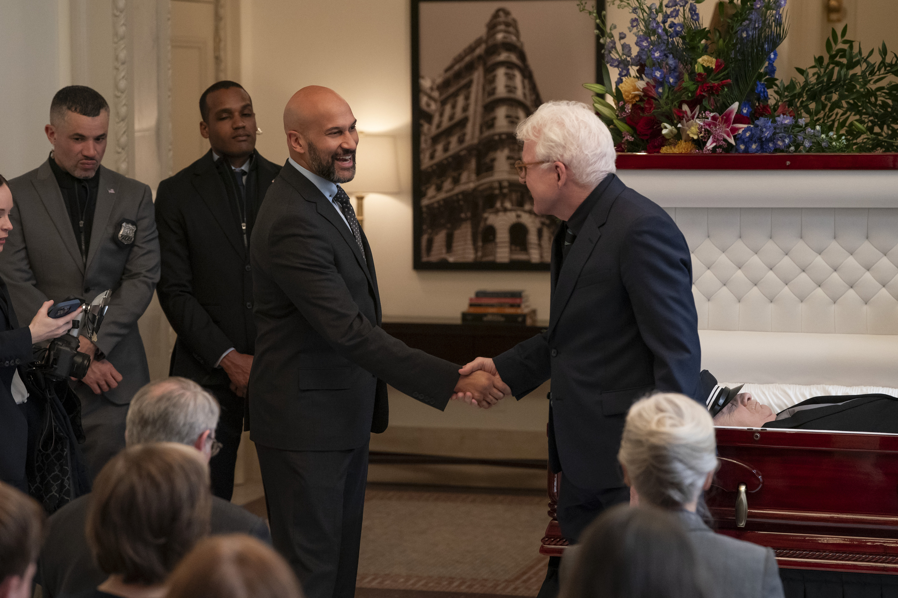 A man (Keegan-Michael Key as Mayor Tillman, center left) shakes another man&#039;s hand (Steve Martin as Charles, center right) as they stand in front of the open casket at a funeral, in &#039;Only Murders in the Building&#039; season 5.
