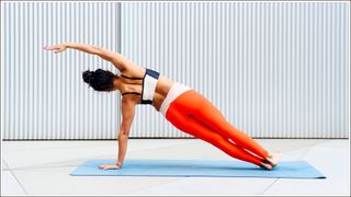 Female sportswoman doing side plank pose in front of wall