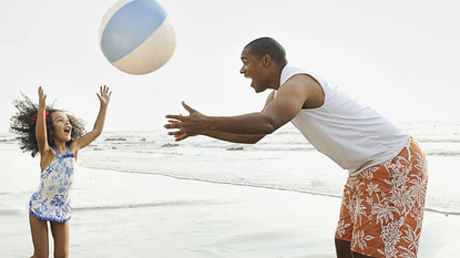 A father and daughter playing with a beach ball.
