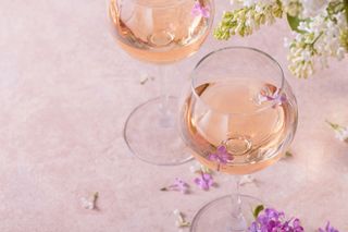 Two glasses of rose wine with some white flowers.