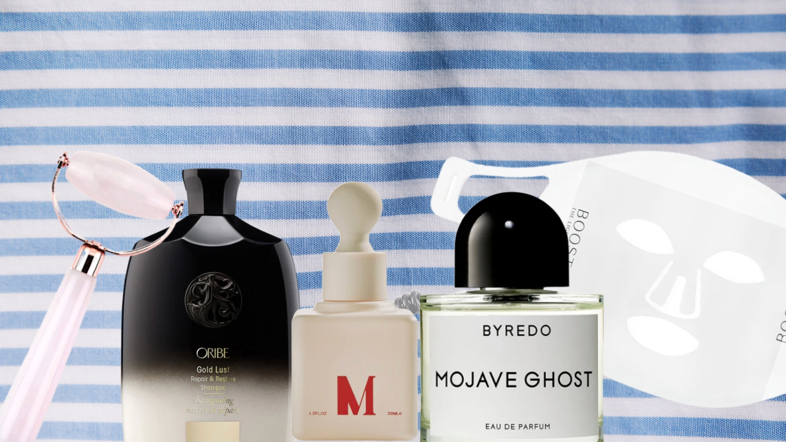 a pink jade roller, oribe shampoo, byredo perfume, dr. diamond serum, and omniluxe face mask on a blue and white stripe towel background