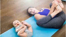 woman and baby on mat doing happy baby yoga pose