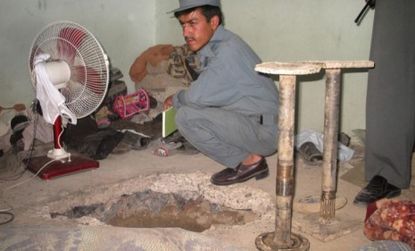 An Afghan policeman examines the hole through which Taliban prisoners escaped from inside Kandahar's main jail.