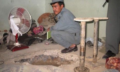 An Afghan policeman examines the hole through which Taliban prisoners escaped from inside Kandahar&amp;#039;s main jail.