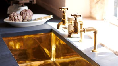 deVOL's shiny brass sink in a dark kitchen