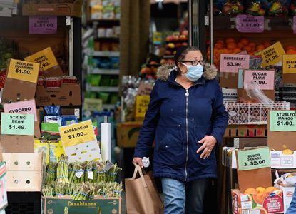 A woman wears a mask while shopping for groceries.