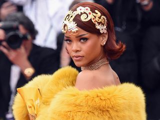 rihanna wears a gold headpiece and a yellow fur cape