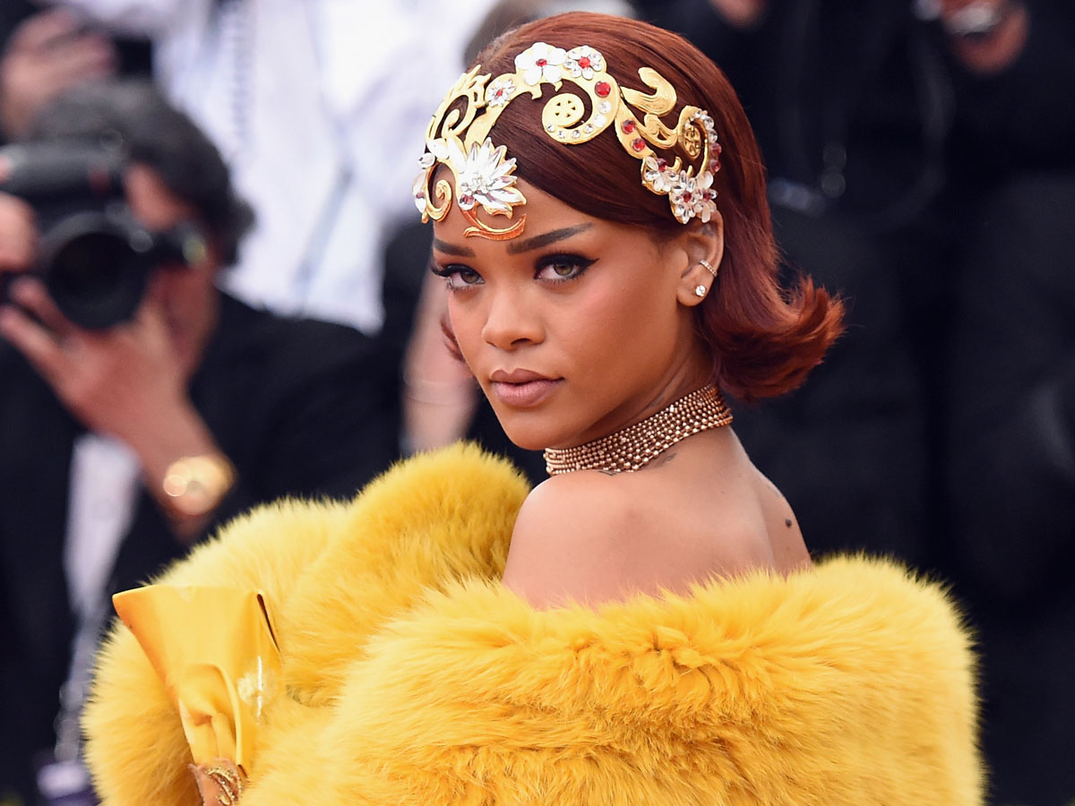 Rihanna wears a gold headpiece and a yellow fur cape at the Met Gala.