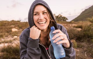 A woman outside drinking a bottle of water