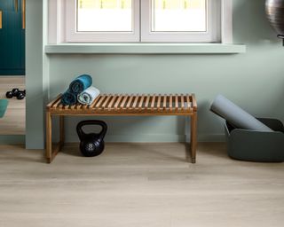 A hallway workout space with wood flooring and wooden bench