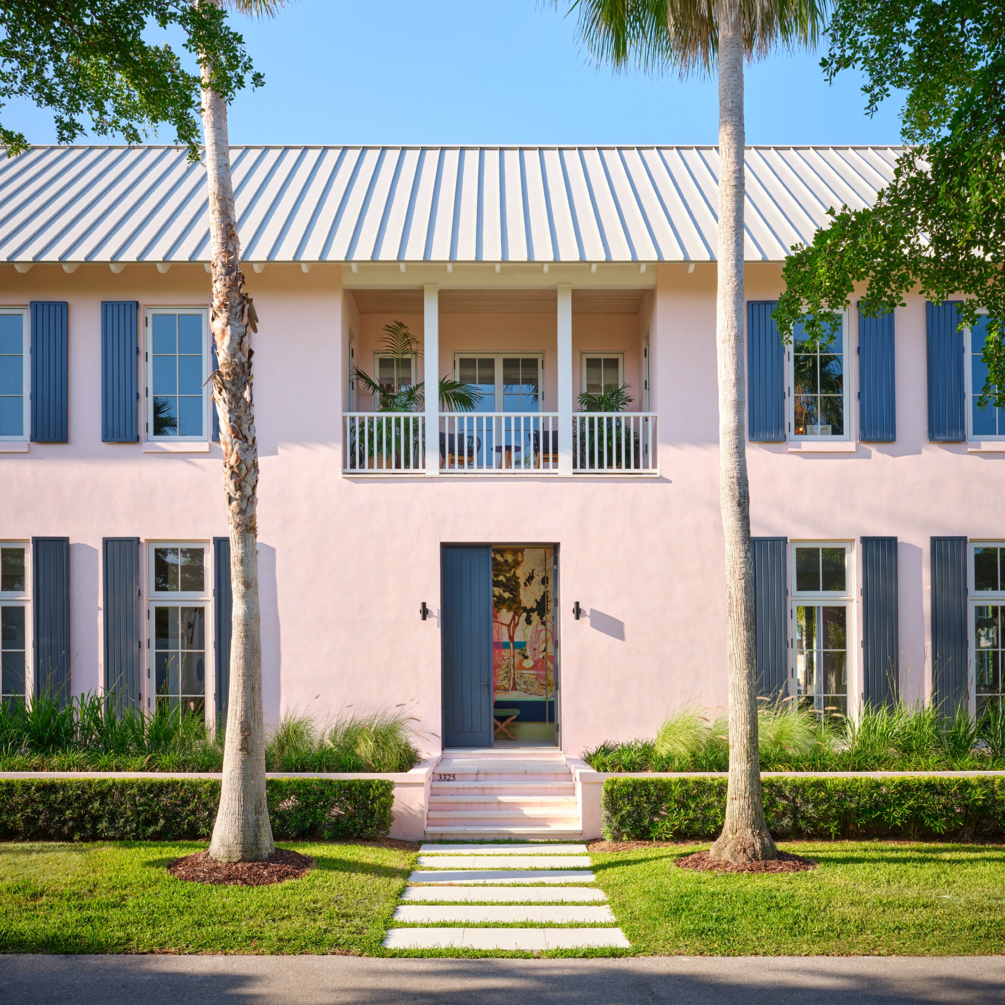 A Florida house painted in Farrow &amp;amp; Ball's Calamine pink shade with the window shutters and front door painted in Farrow &amp;amp; Ball Railings