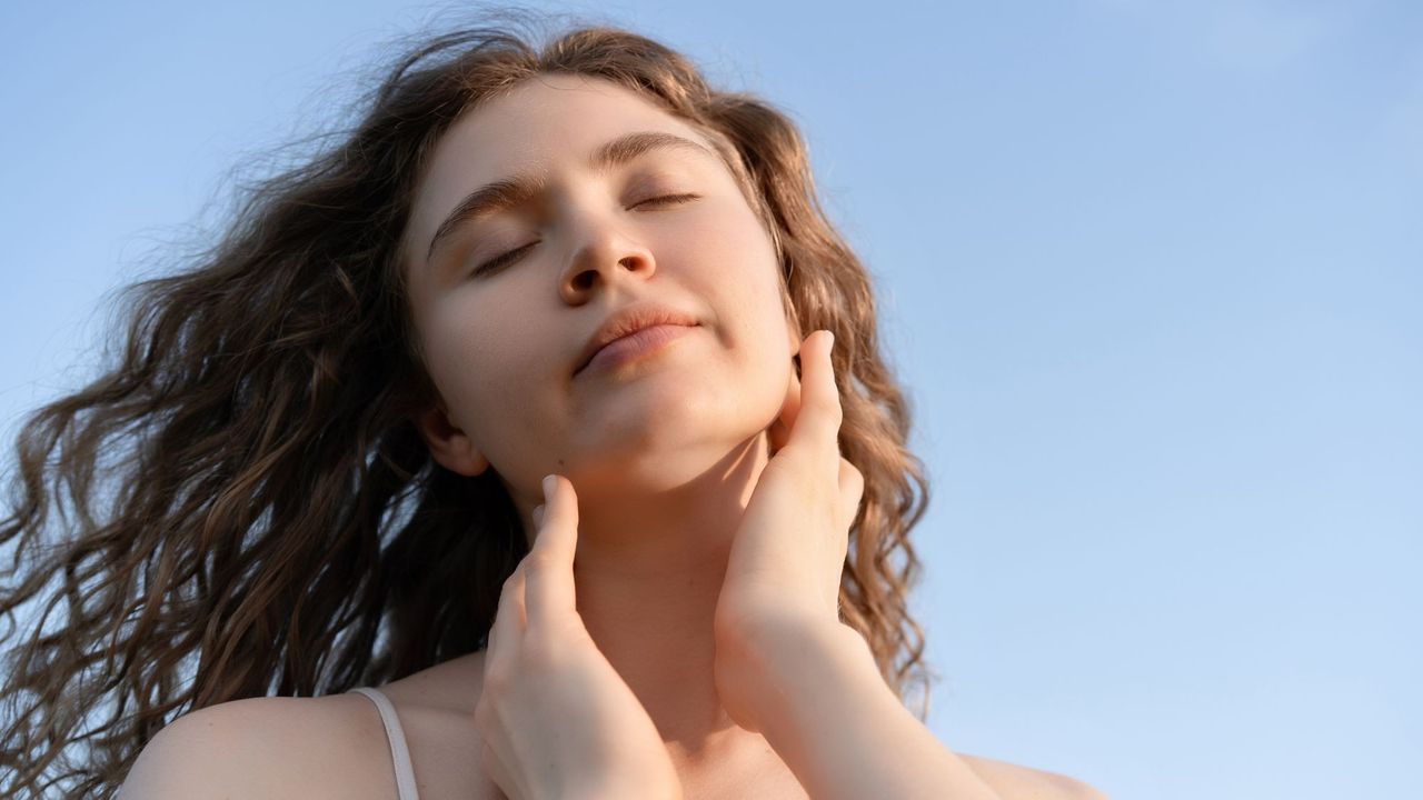 A woman with clear skin holding her face