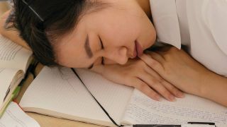 Woman having a nap at her desk, sleep & wellness tips