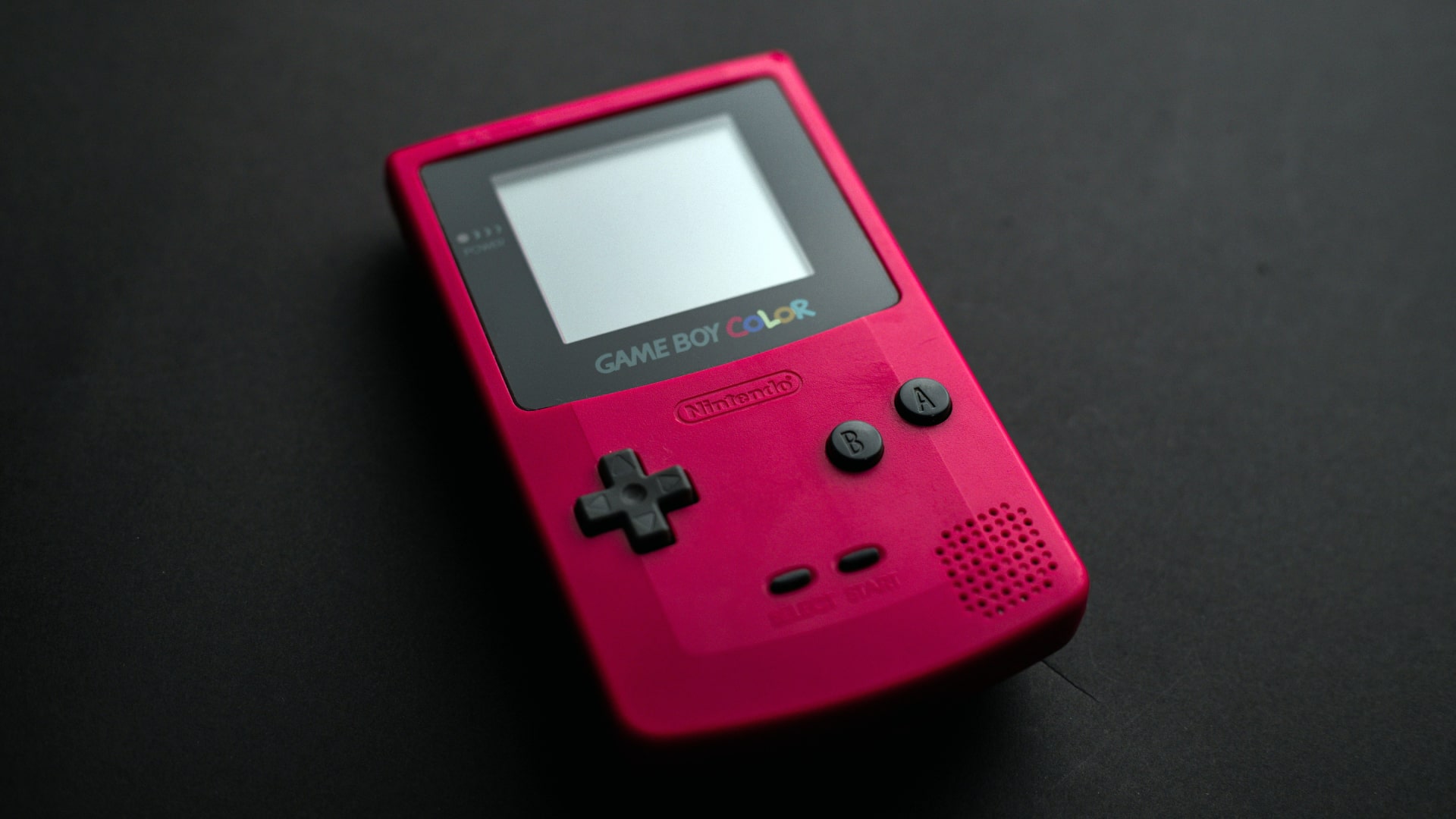 A red Nintendo Game Boy Color lying on a surface.